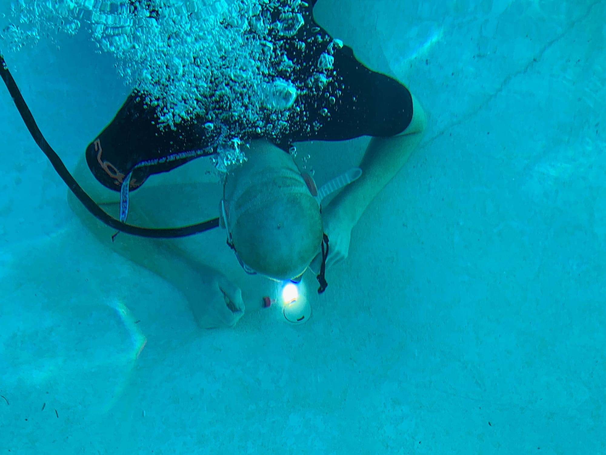 American Leak Detection diver inspecting an underwater pool light for a leak.