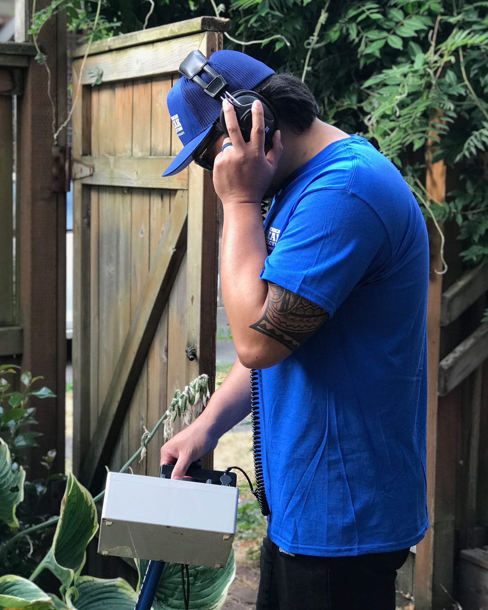 American Leak Detection technician using acoustic listening equipment during an exterior leak diagnostic.