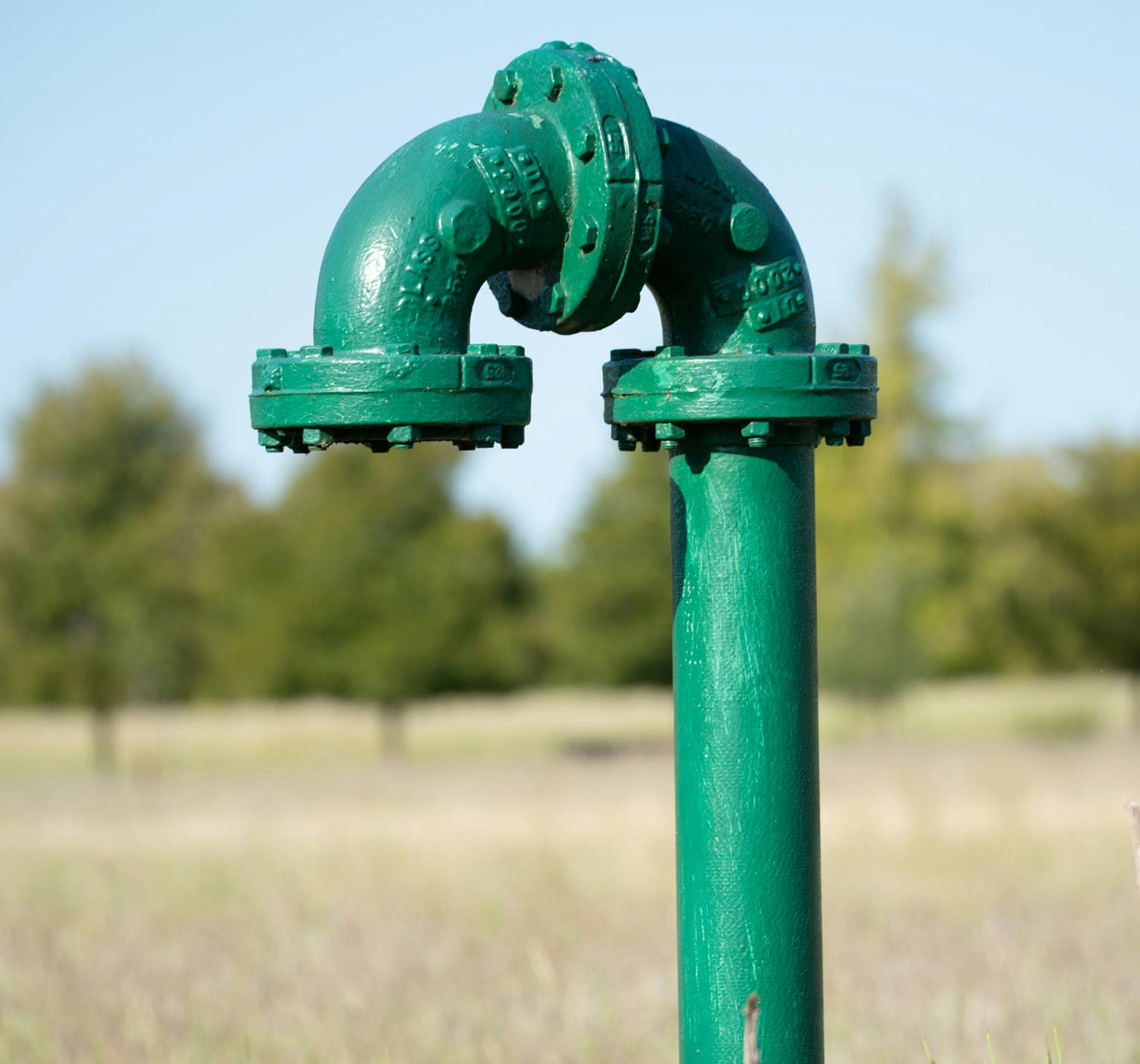 Green water standpipe in an open Butte County field.