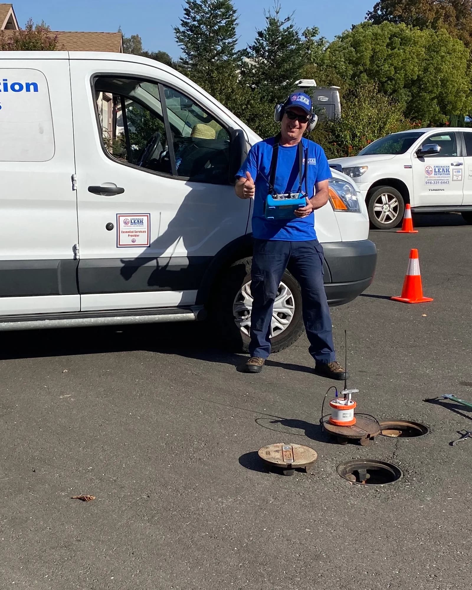 Leak detection technician using acoustic listening equipment beside ALD service vehicles in El Dorado County.