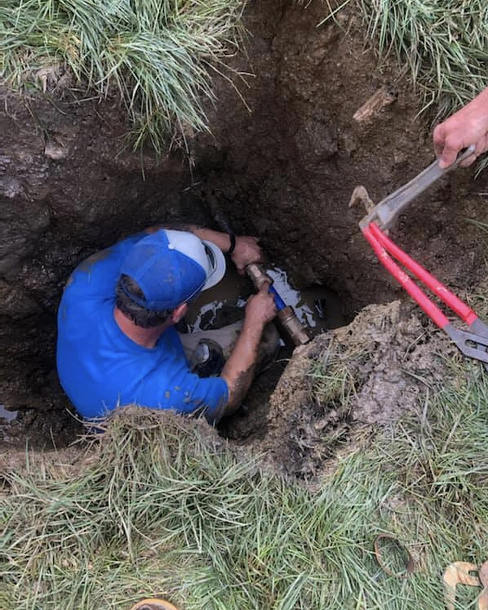 Technician working in an excavated Placer County service-line access pit.