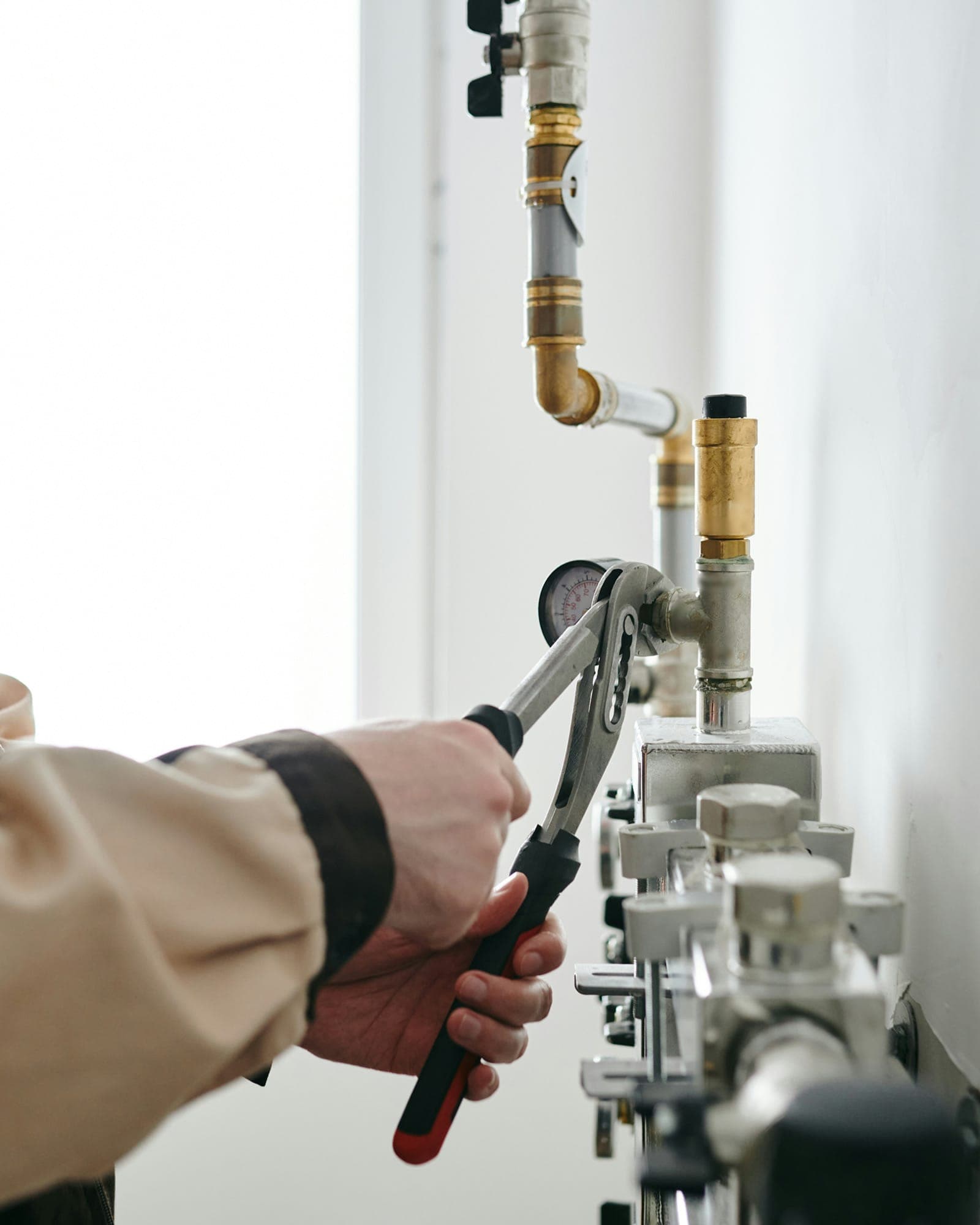 Technician tightening plumbing isolation valves with hand tools during a pressure diagnostic.