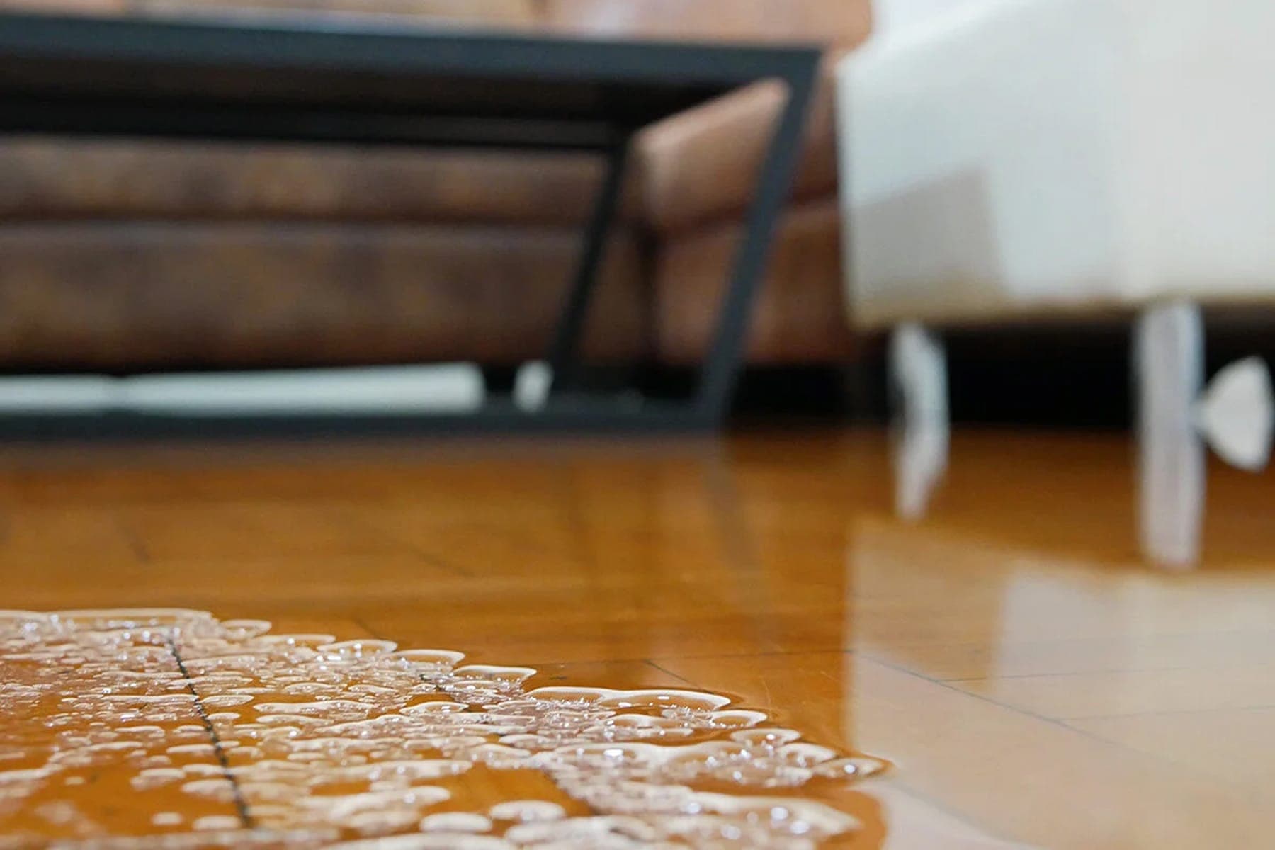 Water spreading across a hardwood floor from an interior leak.