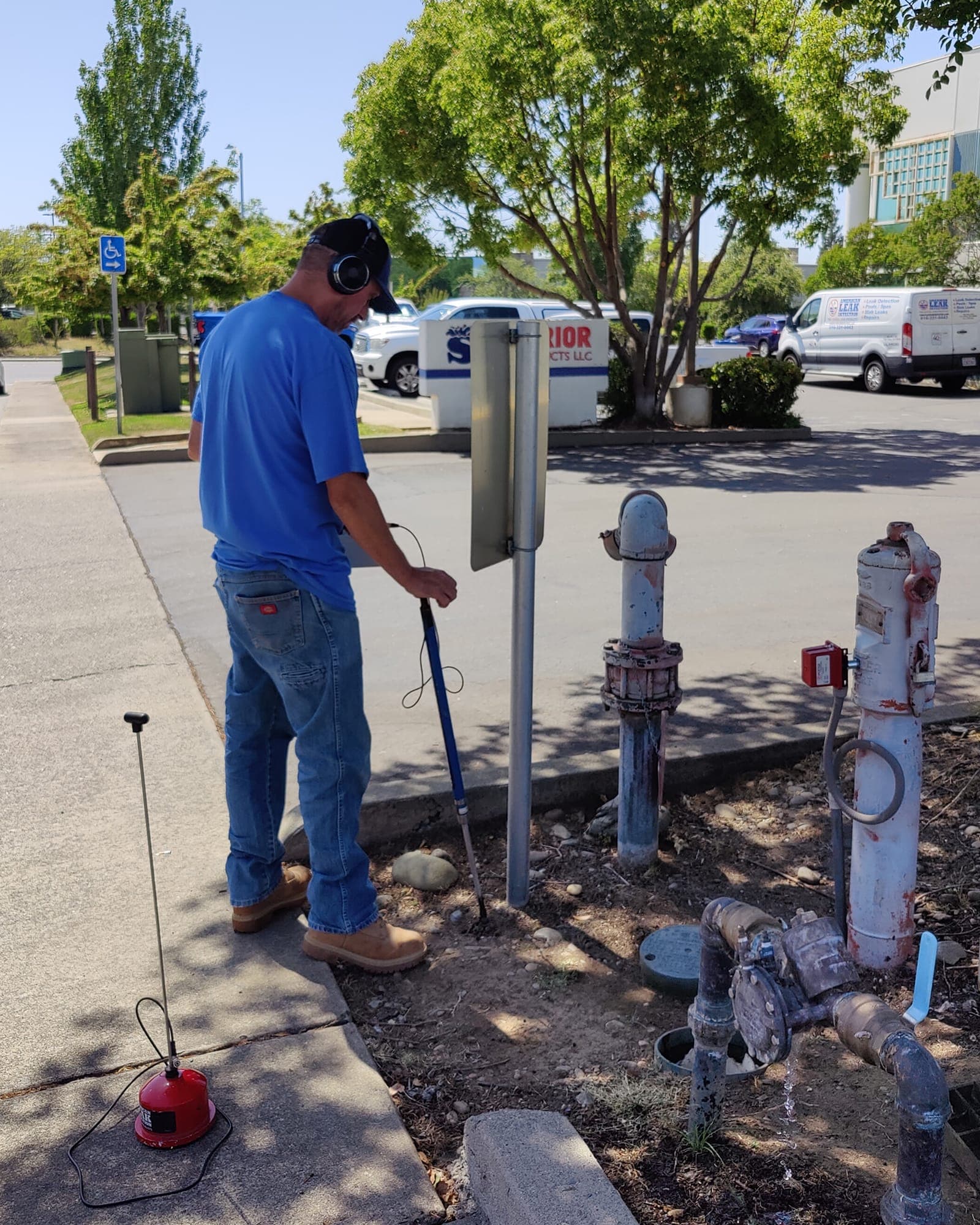 American Leak Detection technician using acoustic listening equipment on exterior plumbing.