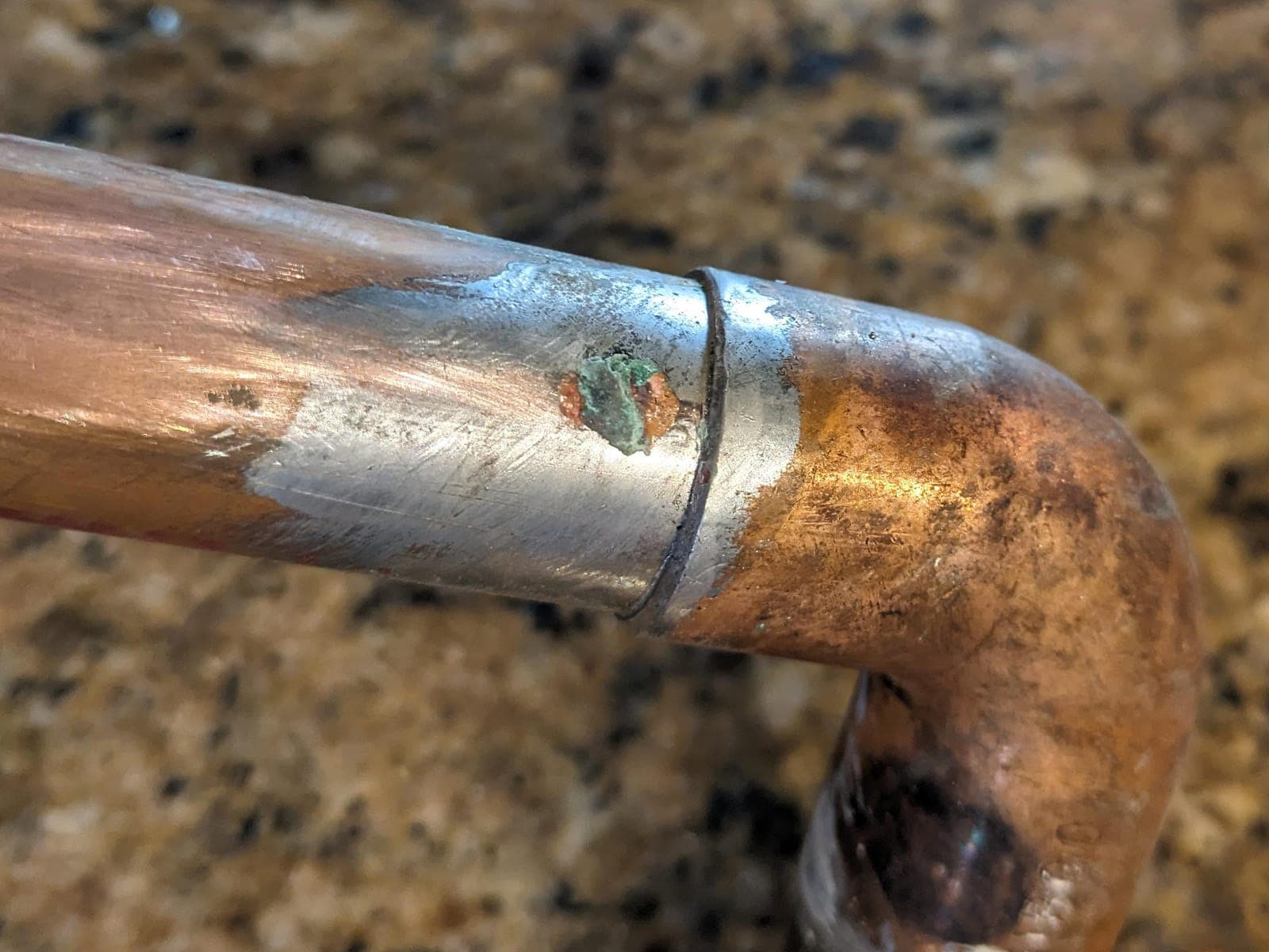 Water condensation on a cold copper pipe in a dim crawlspace.