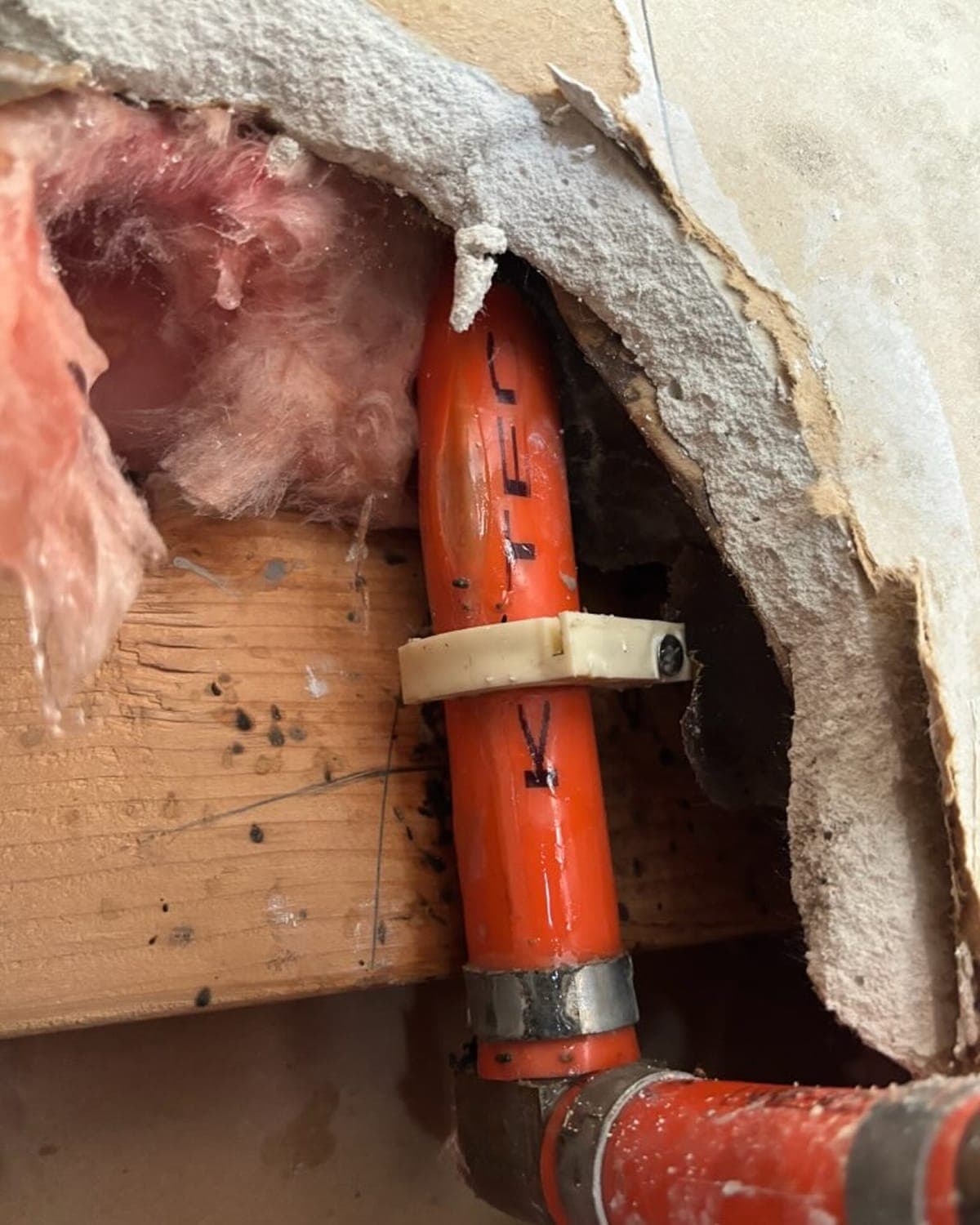 Exposed plumbing inside an opened wall during a water leak investigation.