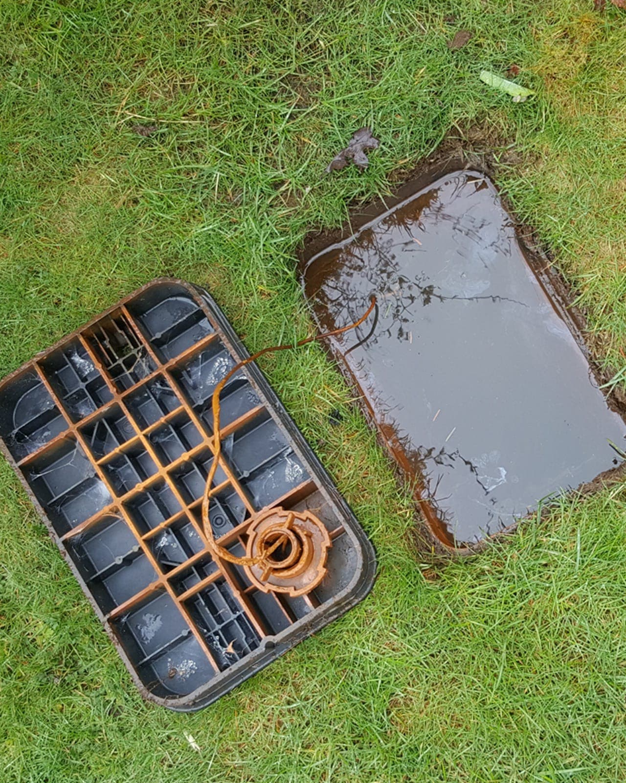 Water pooling around a stuck irrigation valve in an open valve box.