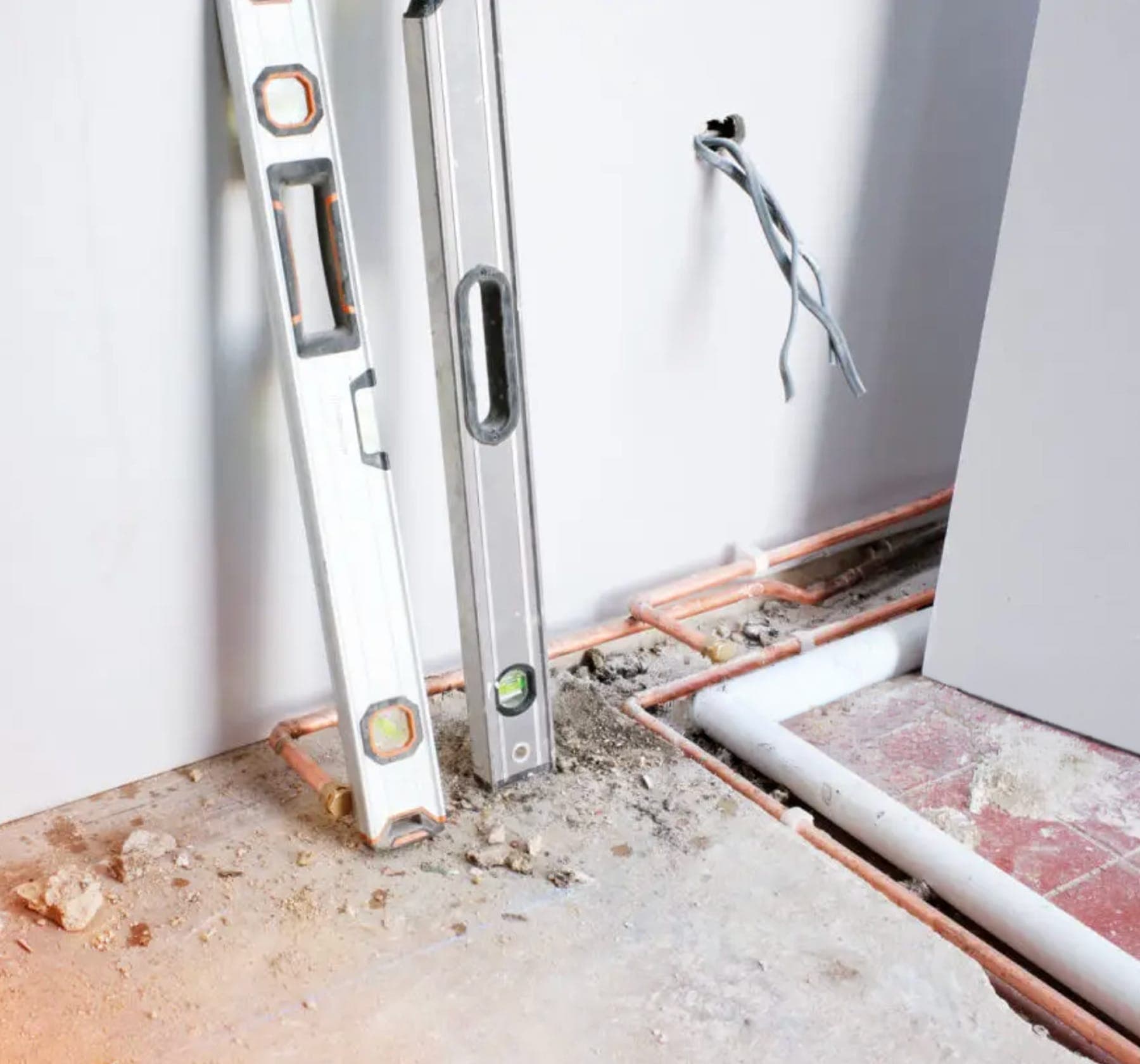 Opened wall and floor area exposing copper plumbing during leak investigation.