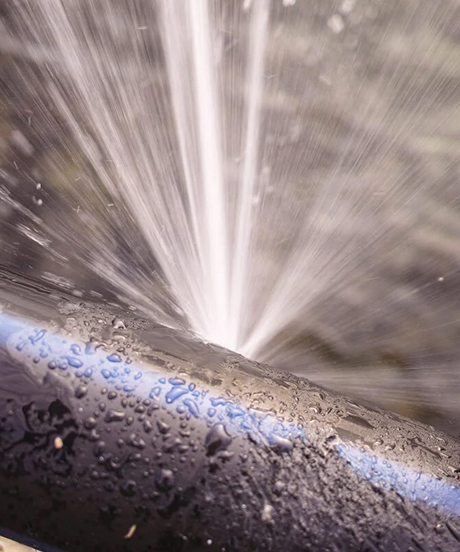 Pressurized pipe spraying water during a leak investigation.
