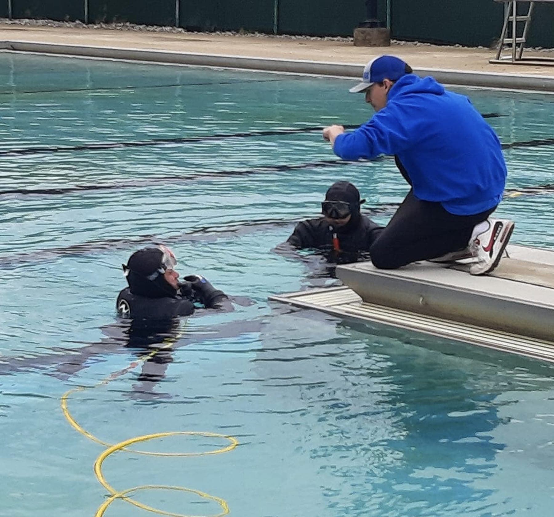 Pool diver and technician inspecting a residential pool for leaks.