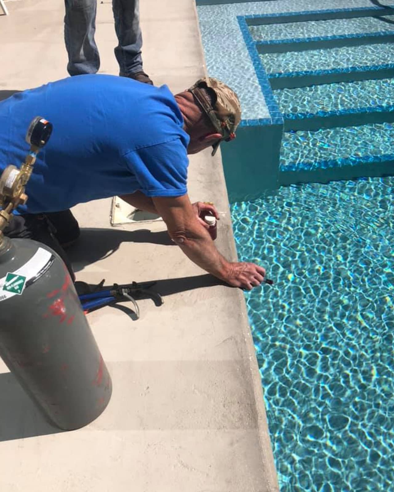 Technician applying leak-detection dye along the pool waterline.