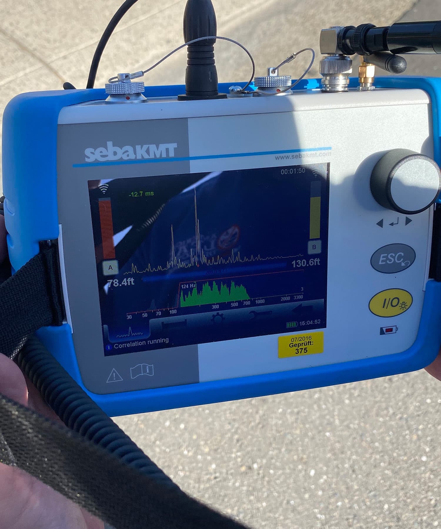 Acoustic leak correlator displaying a live pinpoint reading during a field survey at a managed property.