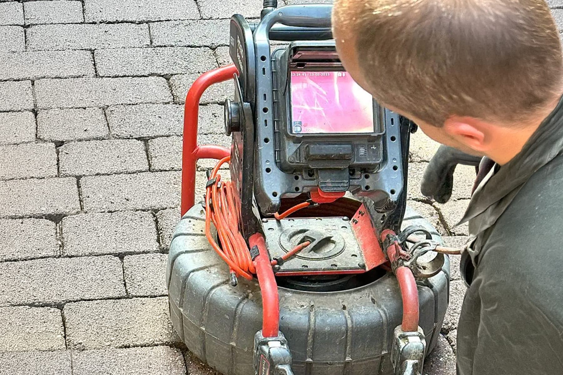 Camera monitor showing the interior of a residential sewer line with visible root intrusion.